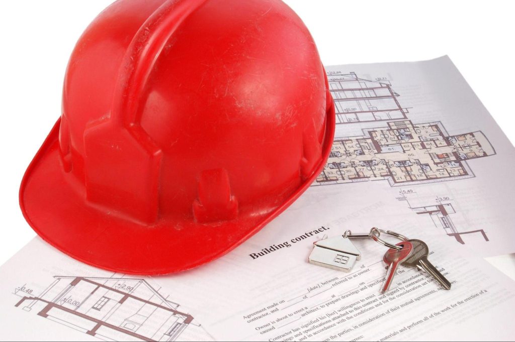 Construction helmet, building contract, and keys on contractor’s desk