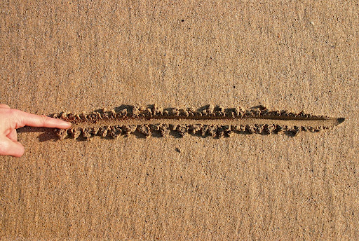 A finger drawing a line in the sand as a visual representation of legal encroachment issues in Utah.