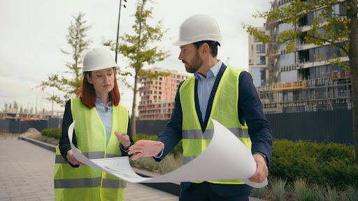 Two construction workers with a blueprint discussing a construction contract dispute.